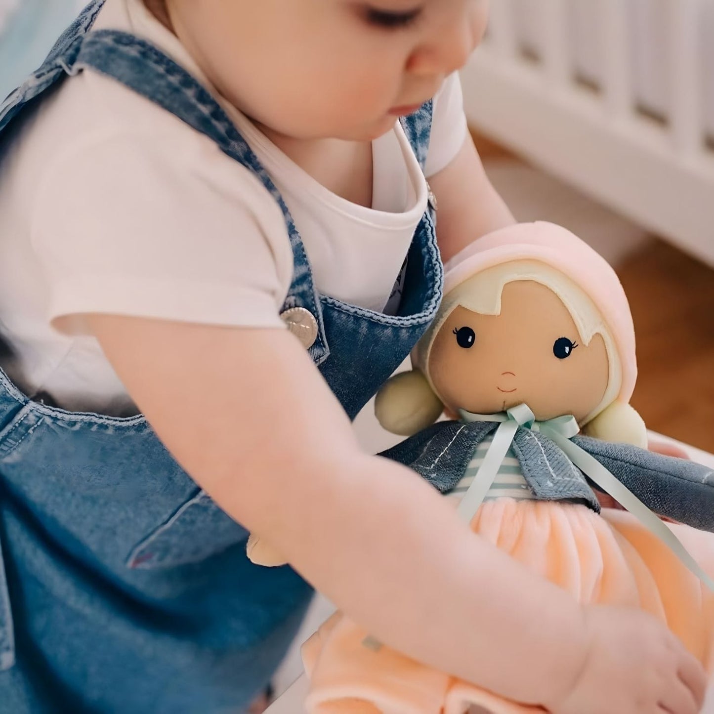 Boneca de Pano Chloe Kaloo com vestido suave, casaco azul e touca rosa em estilo delicado para bebé