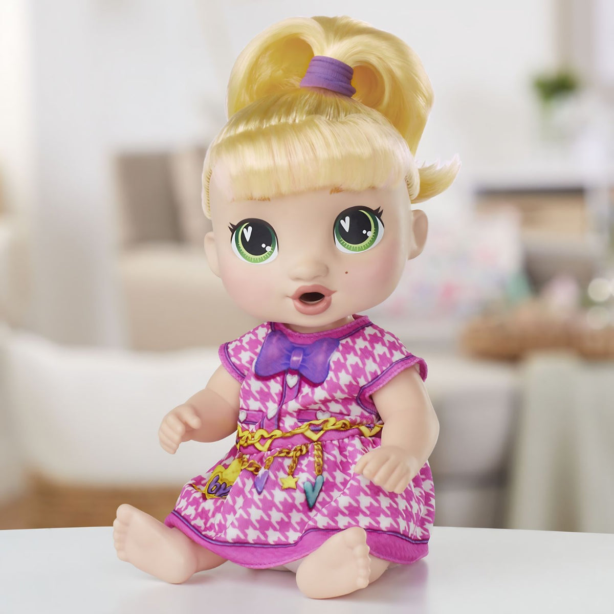 Baby Alive LaLa GooGoo sentada, com cabelo louro preso e vestido rosa e branco