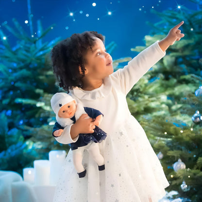 Menina com a boneca Corolle Marguerite Starlit Night ao colo, num cenário noturno