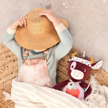Boneco de Atividade Vaca Rosalie junto a uma criança com chapéu de palha