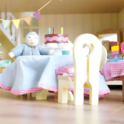 Figura da avó Daisylane à mesa com bolo de aniversário