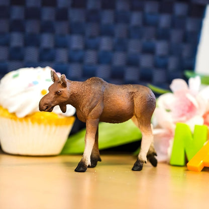 Figura Alce fêmea sobre uma mesa junto a um bolo e flores