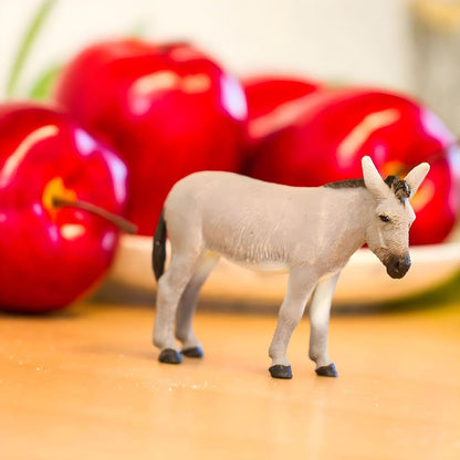Figura de borracha Burro numa mesa junto a maçãs vermelhas