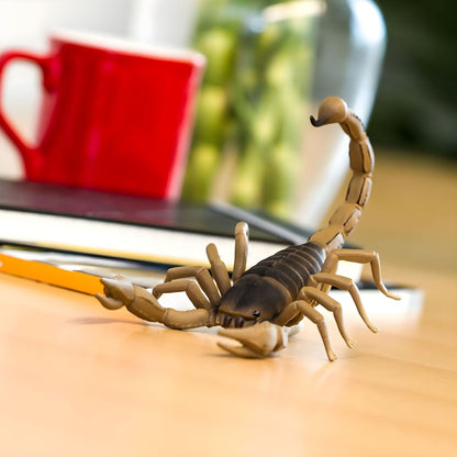 Figura de borracha Escorpião sobre uma mesa junto a uma caneca