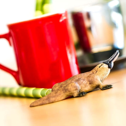Figura de borracha Ornitorrinco numa mesa junto a uma caneca