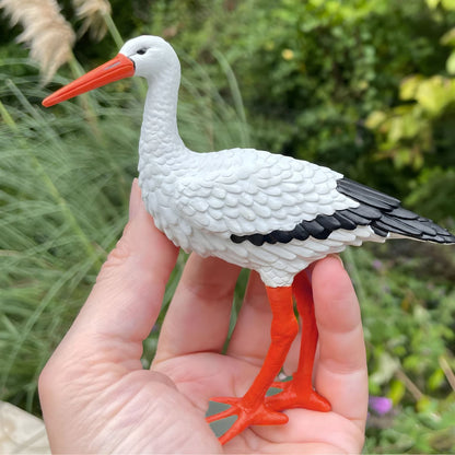 Mão a segurar a Figura de borracha Cegonha-branca num jardim