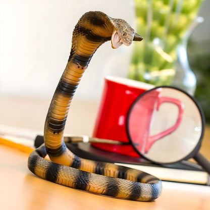 Figura de borracha Cobra sobre uma mesa junto a uma lupa