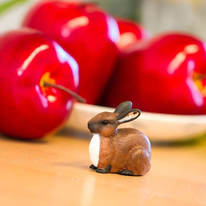 Figura de borracha Coelho sobre uma mesa junto a maçãs vermelhas