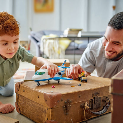 Criança e adulto brincam com o Lego City Jato de Passageiros sobre um baú