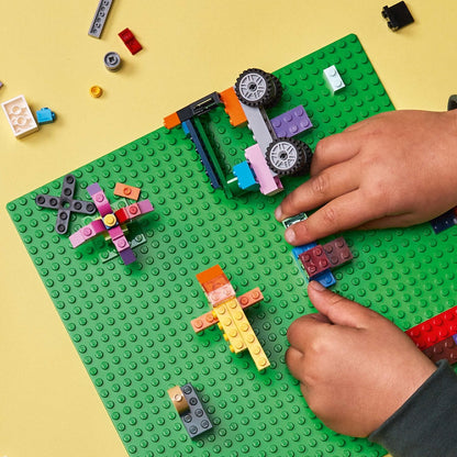 Mãos a construir peças Lego coloridas sobre a Base de Construção Verde
