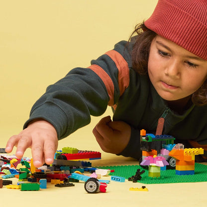 Criança de gorro a construir sobre a Lego Classic Base de Construção Verde