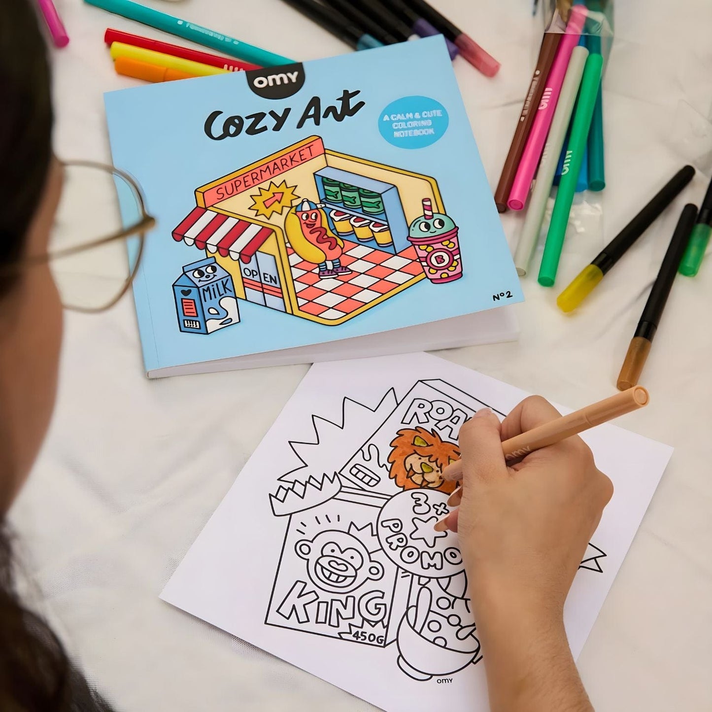 Capa do Livro de colorir Cozy Supermercado da Omy com ilustração de supermercado colorido e personagens divertidas