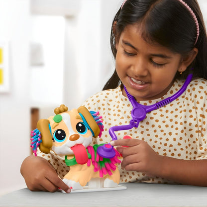 Menina a brincar com o cão do Play Doh Kit veterinário e estetoscópio