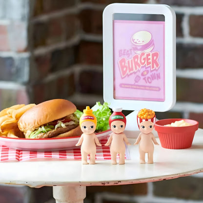 Três figuras Sonny Angel série Snack numa mesa com hambúrguer