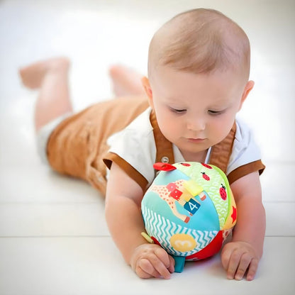 Bebé deitado de barriga a brincar com A Minha Primeira Bola Girafa Sofia