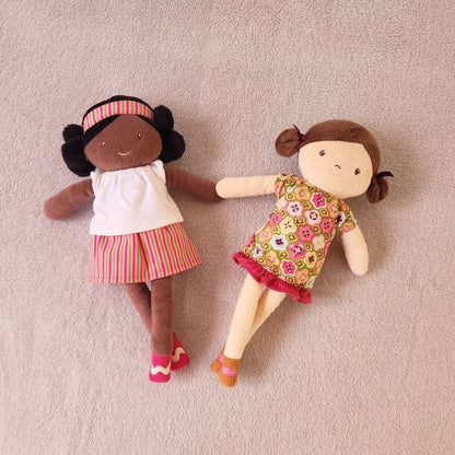 Boneca de Pano Amy 33 cm deitada ao lado de outra boneca de pano com vestido florido