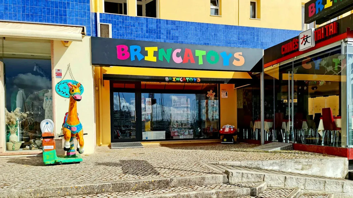 Entrada da loja Brincatoys em Vilamoura, com o letreiro colorido e a girafa junto à porta.