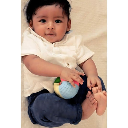 Bebé sentado a sorrir com a Bola de borracha sensorial no colo