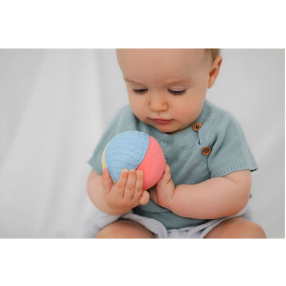 Bebé a segurar a Bola de borracha sensorial com as duas mãos