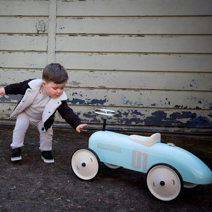Menino a empurrar o Carro de metal Vintage Azul celeste junto a uma parede
