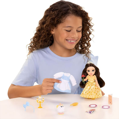 Menina a vestir a boneca Bela do conjunto Princesa Disney numa mesa