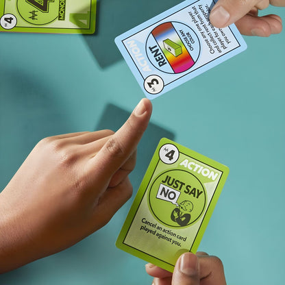Mãos a jogar cartas de ação do Monopoly Deal, incluindo a carta «Just Say No»