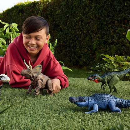 Criança deitada na relva a brincar com o Purussaurus Jurassic World e outros dinossauros