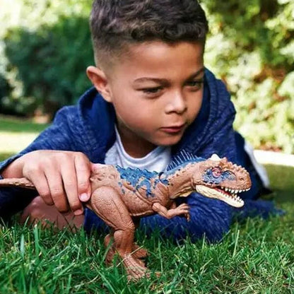 Rapaz deitado na relva a brincar com o Jurassic World Rajasaurus