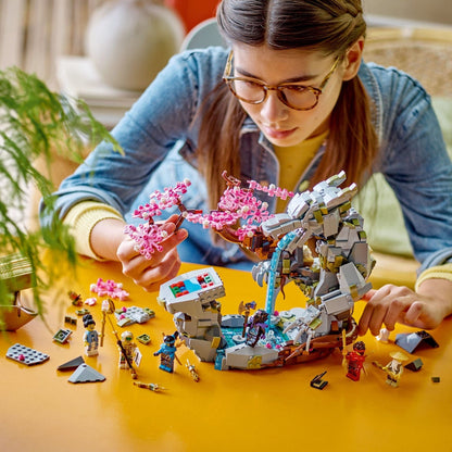 Mulher a montar o LEGO Ninjago Santuário de Pedra do Dragão numa mesa