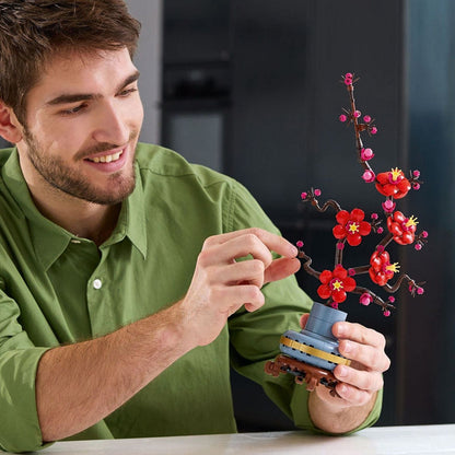 Adulto a montar o LEGO Botanicals 10369 Flor de Ameixa, conjunto de 327 peças para maiores de 18 anos.