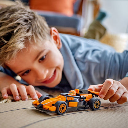 Criança deitada a brincar com o Lego City Piloto de F1 com Carro de Corrida McLaren