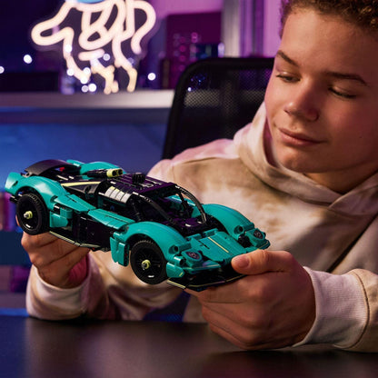 Rapaz segura o Lego Technic Aston Martin Valkyrie montado sobre uma mesa