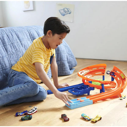Rapaz a brincar com a Pista Hot Wheels em espiral no chão da sala