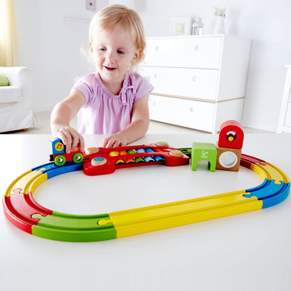 Menina a brincar com a Pista de Comboio sensorial colorida numa mesa