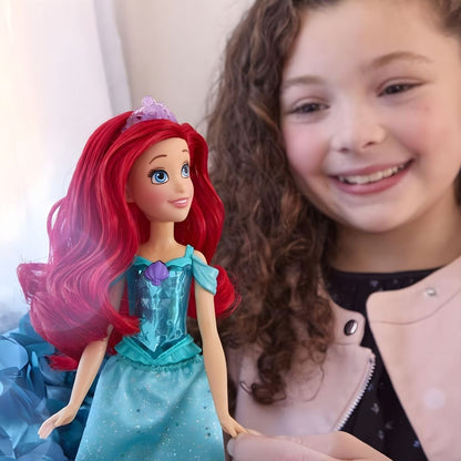 Menina sorridente com a boneca Princesa Disney Ariel Brilho Real