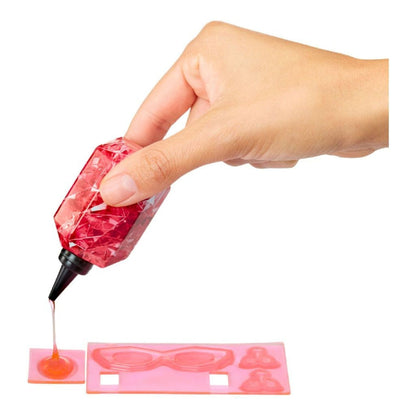 Mão a aplicar gel de cristais vermelho num molde de óculos