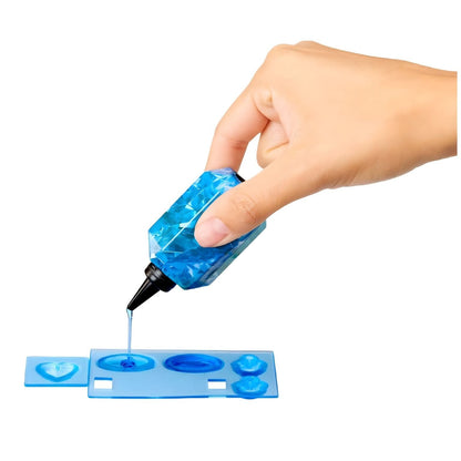 Mão a aplicar gel azul num molde de acessórios da Rainbow High Crystal Skyler