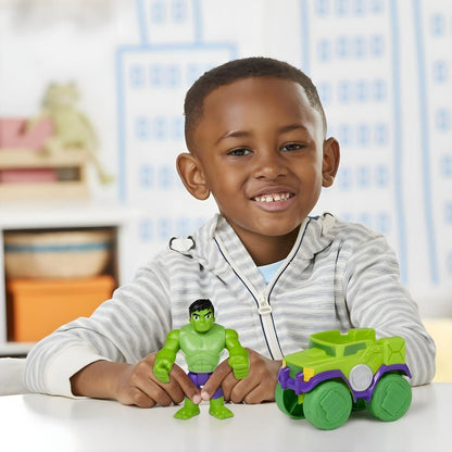 Rapaz sorridente com a figura Hulk e o Hulk Smash Truck numa mesa