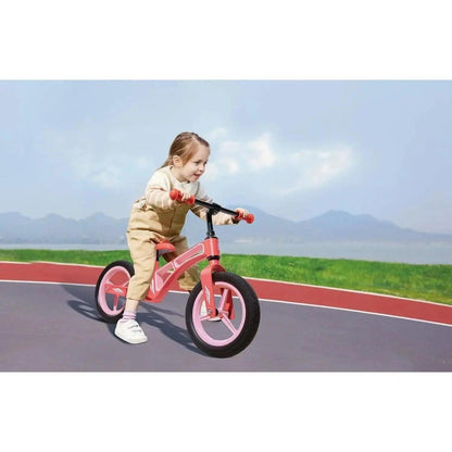 Menina a andar na Bicicleta de Equilíbrio Rosa numa pista ao ar livre