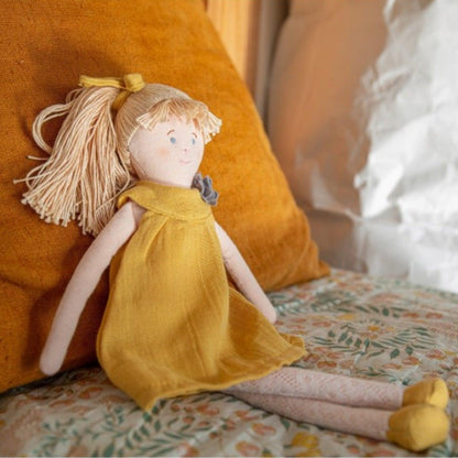 Boneca de Pano com Vestido mostarda encostada a uma almofada