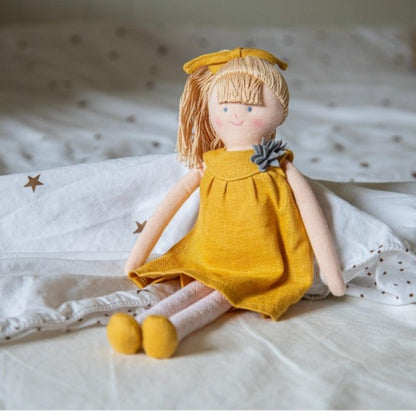 Boneca de Pano com Vestido mostarda sentada numa cama