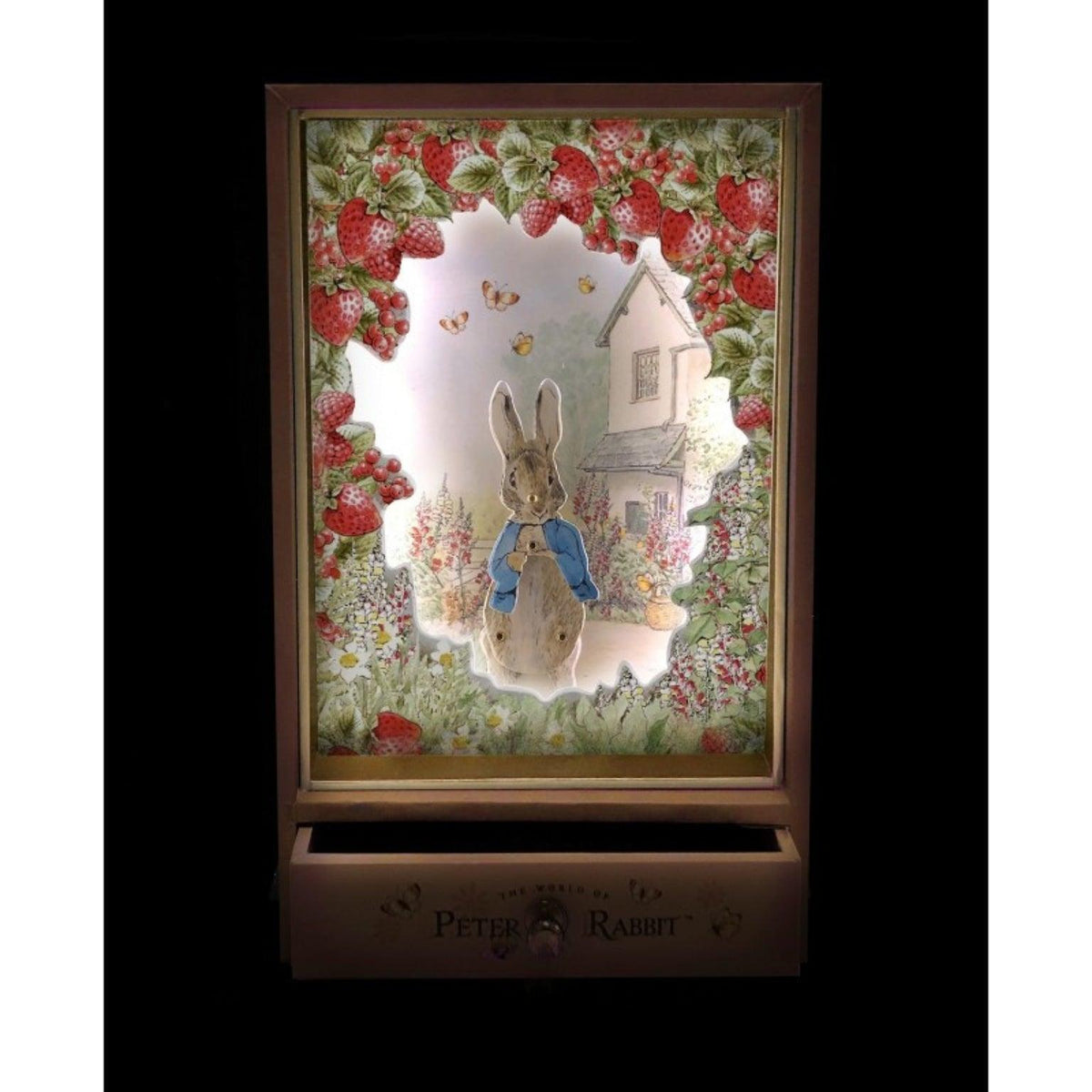 Cena iluminada de Peter Rabbit rodeado de morangos, com a gaveta da caixa musical aberta