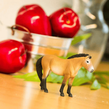 Figura de borracha Cavalo de Przewalski numa mesa junto a maçãs vermelhas