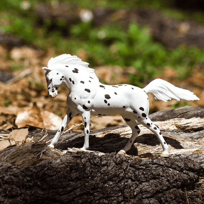 Figura de borracha Cavalo Knabstrupper sobre um tronco na floresta