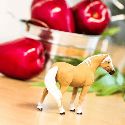 Figura de borracha Égua Palomino numa mesa com maçãs vermelhas atrás