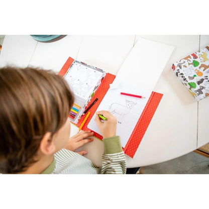 Como desenhar - Na Quinta: criança a desenhar com o conjunto aberto sobre a mesa