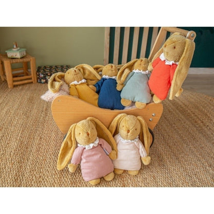 Doudou coelho azul junto a outros coelhos de peluche num cesto de madeira