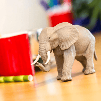 Figura de borracha Elefante Africano numa mesa junto a um copo