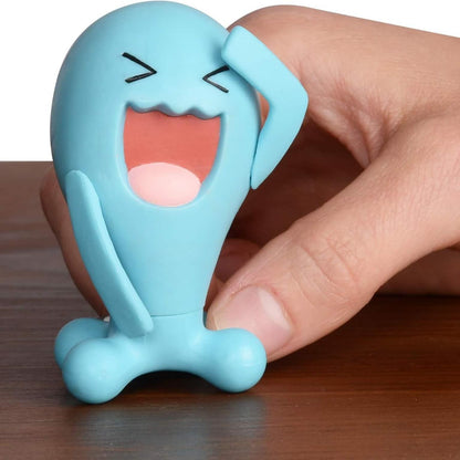Mão a segurar a figura Pokémon Wobbuffet numa mesa