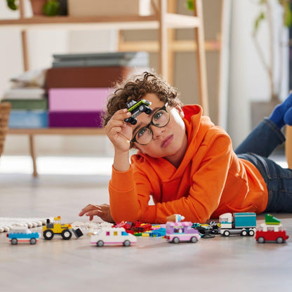 Rapaz deitado no chão a brincar com carros LEGO Classic Veículos Criativos